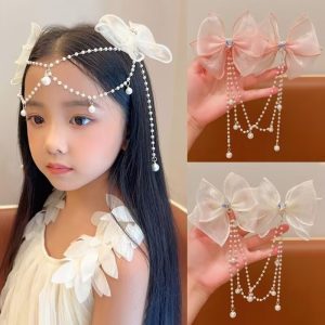 Silver rhinestone bow hairclip attached to a white background, with a dangling pearl chain draped beneath it.